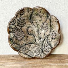 a decorative plate sitting on top of a wooden table next to a white brick wall