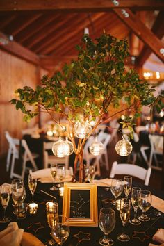 the table is set with wine glasses, candles and a tree