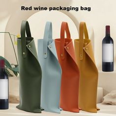 four different colored wine bags next to each other with a bottle in the back ground