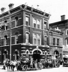 an old black and white photo of horse drawn carriages in front of a brick building