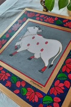 a painting on a table next to a potted plant with red flowers in it