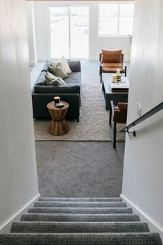 a living room with stairs leading up to the second floor, and a coffee table on the other side