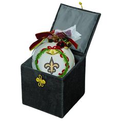 a christmas ornament in a black box with a red ribbon and gold fleur de lis on it