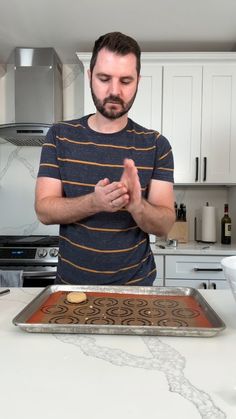 a man standing in front of a pan with food on it and looking at his hands