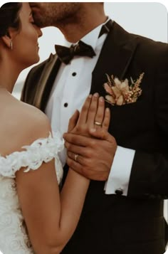 a bride and groom kissing each other in front of the ocean on their wedding day