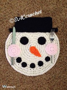 a crocheted snowman placemat with a fork and knife on top of it