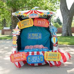 a carnival tent with signs on it and trees in the background