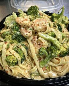 pasta with shrimp, broccoli and sauce in a black bowl on a table