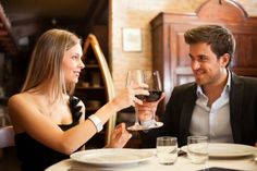 two people sitting at a table with wine glasses