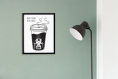 there is a coffee poster hanging on the wall next to a lamp and a chair