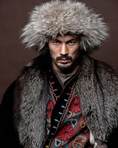 a man wearing a fur hat and coat with an elaborate design on it's hood