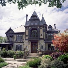 an old victorian style house with stone steps and landscaping around the front door, on a cloudy day