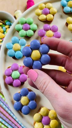 a person is holding a candy stick in their hand and there are many candies on the plate