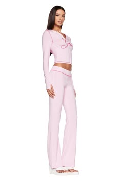 A woman stands posing in a full-length, side view. She is wearing a light pink, long-sleeved top with J'Adore written on it and matching pastel pink BLARE TRACKPANT from I.AM.GIA. She has long, straight hair and is wearing white, open-toe platform sandals. I Am Gia Pink Set, Pink Sets Outfit, Pink Iamgia Set, Streetwear Fashion Pink, 2 Piece Lounge Set Outfit, Girlalala Outfits, Cute Sets Two Pieces, Pink Set Outfit, Pink Streetwear Outfit