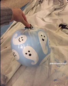 someone is painting a blue pumpkin with ghost faces