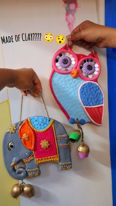 a person holding an owl shaped purse next to a wall hanging elephant ornament