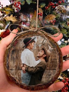 a man and woman are hugging each other in front of a christmas tree ornament