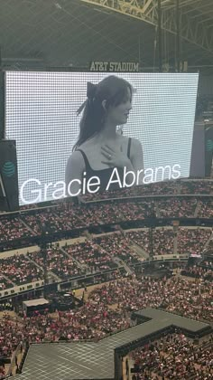 a woman is standing in front of a large screen at a tennis match, with the words crackie abrahams on it