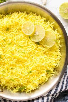 a pan filled with rice and lemons on top of a table next to sliced limes