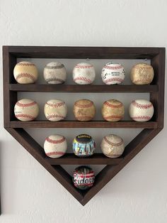 several baseballs are displayed on a shelf in the shape of a triangle, and one is empty