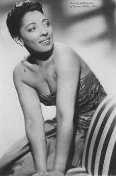 an old black and white photo of a woman posing on a striped chair with her legs crossed