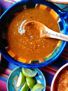 a blue bowl filled with soup next to bowls of limes and other food items