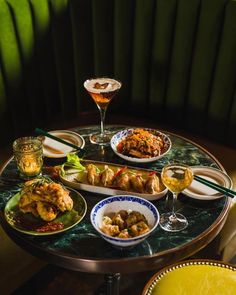 a table topped with plates and bowls filled with different types of food next to drinks