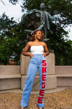 a woman standing in front of a statue with her hands on her hips and wearing high waist jeans