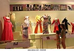 people are looking at dresses on display in a room with many mannequins