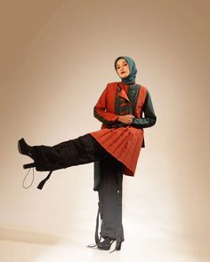 a woman is sitting on the back of a chair wearing a red dress and black pants