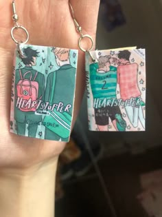 Heartstopper comic book earrings! Size: Length: 4cm Width: 2.5cm  Depth: 0.5m  Pictured next to my hand so you can get an idea of it's size  I love the heartstopper books and was inspired to make tiny little earrings out of them!  They're made by hand by me and as such aren't all exactly the same, so please excuse any small imperfections that come with handmade items ❤️ All Heartstopper Books, Heartstopper Earrings, Heartstopper Graphic Novel, Heartstopper Books, Bisexual Wallpaper Iphone Aesthetic, Reading Sheet Music, Bookshelf Art