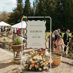 a sign that says elizabeth and lucas on it next to some potted plants with people in the background