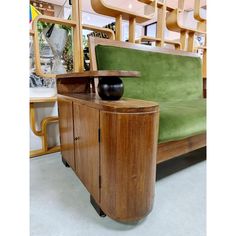 a green couch sitting next to a wooden cabinet