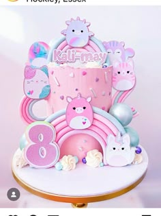 there is a pink cake with animals on it and the number eight next to it