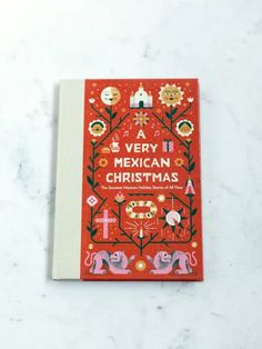 a very mexican christmas book sitting on top of a white marble countertop with an orange cover