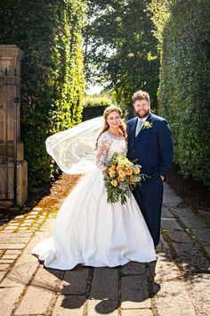 a bride and groom pose for a photo in front of an archway at their wedding