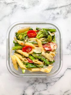 a glass bowl filled with pasta and vegetables