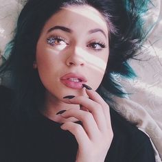 a woman laying on top of a bed with green hair