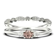 a pink diamond ring set on top of a white gold band with diamonds around it