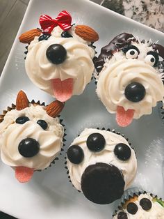 cupcakes with frosting and decorations on top of a white plate in the shape of dogs