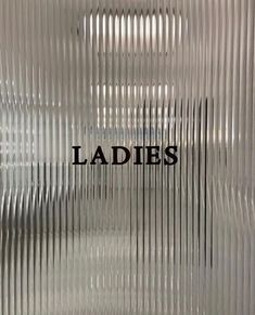 the words ladies are etched on a shiny glass surface with vertical lines in black and white