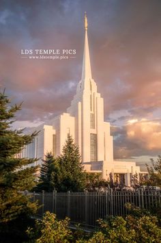 a large white church with a steeple and fence around it's perimeter under a cloudy sky