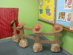 some paper mache hats are placed on top of wooden posts in front of a green wall