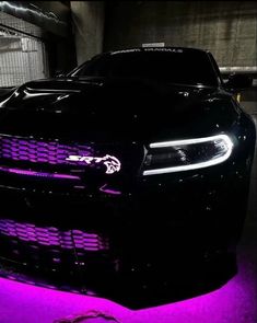 the front end of a black car with purple lights