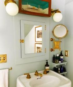 a bathroom sink sitting under a mirror next to a white counter top with gold faucets