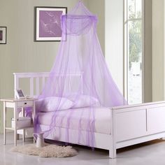 a white bed with a purple mosquito net on it's headboard and foot board