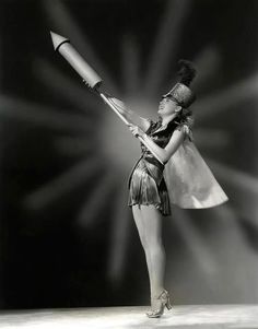 a woman in a short skirt holding a large metal object with one arm and two legs