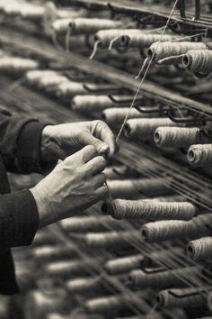 an old woman is working on some type of thread in a machine room with many spools of thread