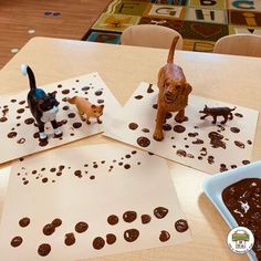 three dogs and one cat are made out of chocolate chips on the table with paper