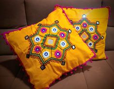 two decorative pillows sitting on top of a couch next to each other with colorful designs